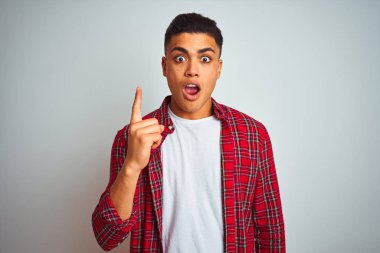 Kırmızı gömlek giyen genç Brezilyalı adam başarılı bir fikir ile parmak işaret izole beyaz arka plan üzerinde duruyor. Çıktı ve mutlu. Bir numara.