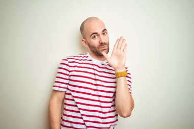 Sakallı genç kel adam beyaz izole arka plan üzerinde rahat çizgili kırmızı t-shirt giyen merhaba mutlu ve gülümseyen, samimi hoş geldin jesti söyleyerek Waiving