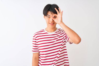 Izole beyaz arka plan üzerinde duran rahat çizgili t-shirt giyen genç Çinli adam el gülümseyerek ok jest yapıyor, mutlu yüz ile parmakları ile bakarak göz.
