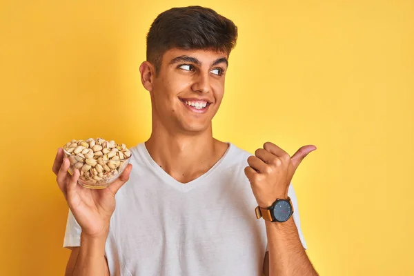 Young Indian Man Holding Bowl Pistachios Isolated Yellow Background Pointing — Stock Photo, Image