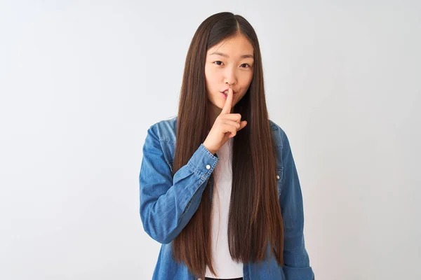 年轻的中国妇女穿着牛仔衬衫站在孤立的白色背景上 要求用手指在嘴唇上保持安静 沉默和秘密概念 — 图库照片