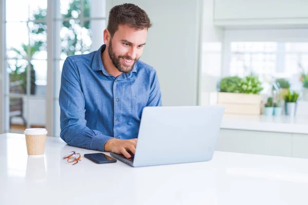 Hombre de negocios guapo trabajando con computadora portátil y sonriendo — Foto de Stock