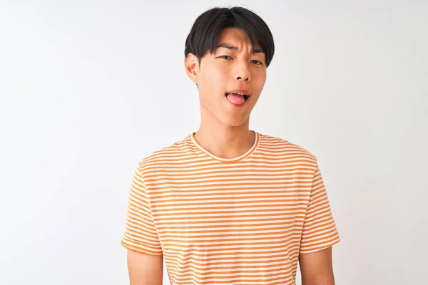 カジュアルなストライプのTシャツを着た若い中国人男性は 孤立した白い背景の上に立ち おかしな表情で舌を突き出す 感情の概念 — ストック写真