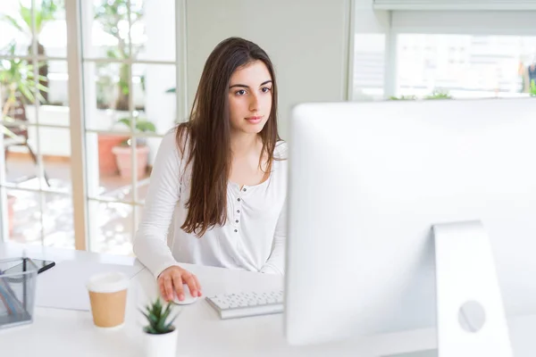 Schöne junge Geschäftsfrau, die mit Computer arbeitet, lächelnd ein — Stockfoto