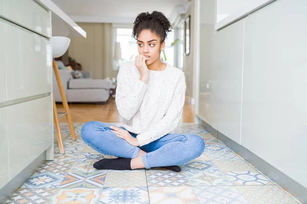 美丽的年轻非洲裔美国妇女 头发坐在地板上 看起来紧张和紧张 手在嘴咬指甲 焦虑问题 — 图库照片