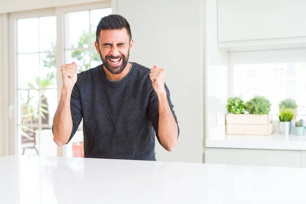英俊的西班牙男子穿着休闲毛衣在家里兴奋的成功与手臂提出庆祝胜利微笑 优胜者概念 — 图库照片