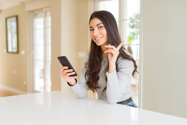 Młoda Kobieta Pomocą Smartfona Wysyłanie Wiadomości Bardzo Szczęśliwy Wskazując Ręką — Zdjęcie stockowe
