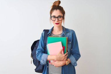 Redhead öğrenci kadın ciddi düşünme akıllı yüz üzerinde emin bir ifade ile izole beyaz arka plan üzerinde kitap tutan sırt çantası giyen