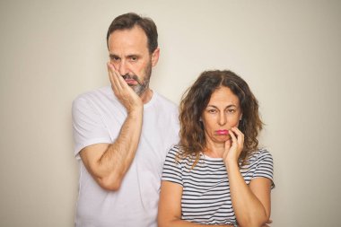 Güzel orta yaş çift birlikte izole beyaz arka plan üzerinde yorgun görünümlü ve çapraz kolları ile depresyon sorunları ile sıkılmış düşünme üzerinde duran.