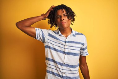 Afro amerikan adam dreadlocks izole sarı arka plan üzerinde çizgili gömlek giyen kafa karıştırıcı ve soru hakkında merak ediyorum. Şüpheyle belirsiz, eliyle kafada düşünmek. Pensive kavramı.