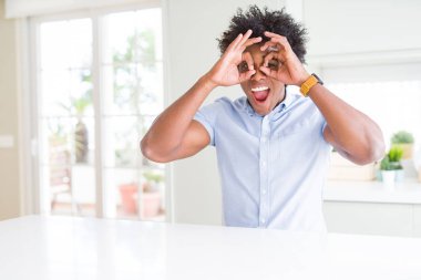 Afro-Amerikan iş adamı dürbün dil dışarı sopa gibi ok jest yapıyor, gözleri parmaklardan bakarak. Çılgın ifade.
