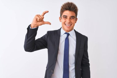 Genç yakışıklı işadamı izole beyaz arka plan üzerinde duran takım elbise giyen gülümseyerek ve emin el parmakları görünümlü ve kamera ile küçük boyutlu işareti yapıyor gesturing. Ölçü kavramı.