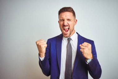 Beyaz izole arka plan üzerinde genç yakışıklı iş adamı çok mutlu ve heyecanlı kolları kaldırdı ile kazanan jest yapıyor, gülümseyerek ve başarı için çığlık. Kutlama konsepti.