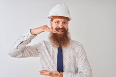 Genç kızıl İrlandalı mimar adam izole beyaz arka plan üzerinde güvenlik kask giyen elleri büyük ve büyük boy işareti gösteren gesturing, ölçü sembolü. Kameraya bakarak gülümsüyor. Ölçme kavramı.