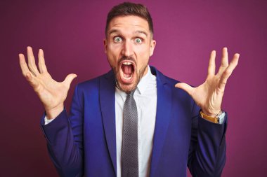 Mor izole arka plan üzerinde genç yakışıklı iş adamı deli kutluyor ve kollarını kaldırdı ve açık gözleri heyecanlı çığlık ile başarı için hayran. Kazanan kavramı