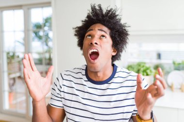 Afro-Amerikan adam çizgili t-shirt deli ve deli bağırarak giyen ve agresif ifade ve kollar kaldırdı ile bağırıyor. Hayal kırıklığı kavramı.