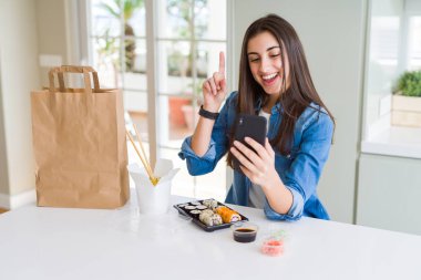 Akıllı telefon kullanarak uygulamadan yemek teslimatı sipariş eden güzel genç kadın, bir numaralı mutlu yüzlü bir fikir ya da soru işaret parmağıyla şaşırttı