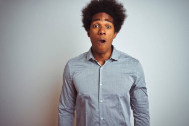 Izole beyaz arka plan üzerinde gri gömlek giyen afro saçlı genç afro-Amerikan adam korkmuş ve sürpriz ifade ile şok, korku ve heyecanlı yüz.