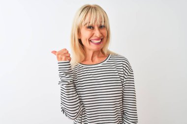 Orta yaş kadın lacivert çizgili t-shirt izole beyaz arka plan üzerinde mutlu yüz görünümlü gülümseyerek ayakta giyen ve başparmak yukarı ile yan işaret.