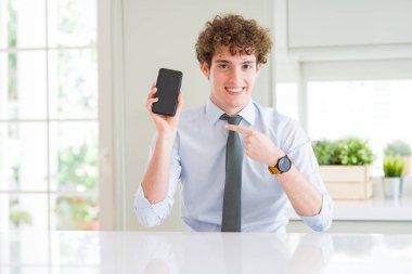 Ofiste akıllı telefon ekranını gösteren genç iş adamı el ve parmakla işaret etmekten çok mutlu