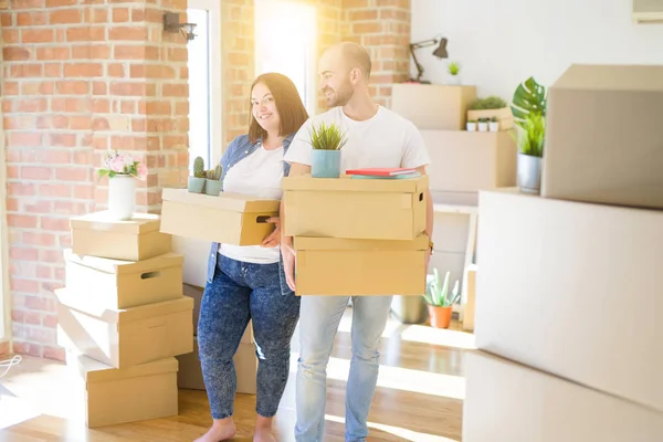 Pareja joven mudándose a un nuevo hogar, sonriendo feliz sosteniendo cardboa — Foto de Stock