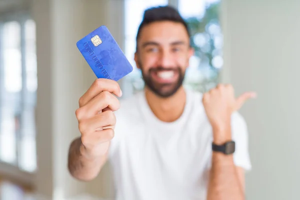 Hombre Hispano Guapo Sosteniendo Tarjeta Crédito Señalando Mostrando Con Pulgar —  Fotos de Stock