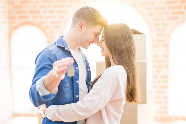 Bonito jovem casal abraçando no amor e mostrando as chaves do novo h — Fotografia de Stock