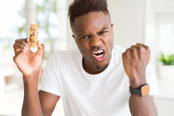 Αφρικανός Αμερικανός Άνθρωπος Τρώει Ενεργητικές Μπαρ Δημητριακά Ενοχλημένος Και Απογοητευμένοι — Φωτογραφία Αρχείου