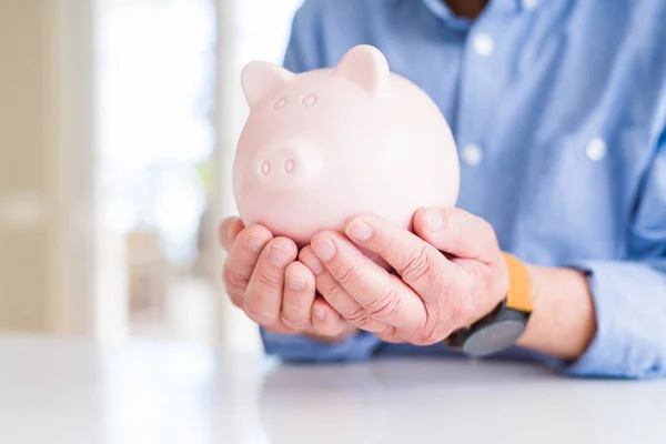 Man piggy houderbank zorgvuldig, geld sparen voor pensioen — Stockfoto