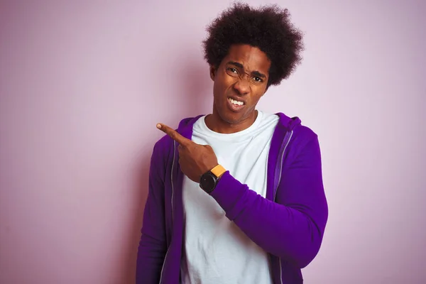 孤立したピンクの背景の上に立つ紫色のスウェットシャツを着た若いアフリカ系アメリカ人男性は 人差し指で心配と緊張を脇に置き 心配し 驚いた表情を示す — ストック写真
