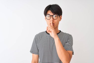 Gözlük ve lacivert çizgili t-shirt giyen Çinli adam dudaklarında parmak ile sessiz olmak isteyen izole beyaz arka plan üzerinde duruyor. Sessizlik ve gizli kavram.