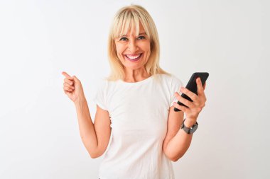 Orta yaş kadın izole beyaz arka plan üzerinde duran akıllı telefon kullanarak çok mutlu yan el ve parmak ile işaret