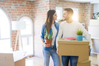 Güzel genç çift yeni bir ev, yeni bir dairede mutlu tutan karton kutular gülümseyen hareket