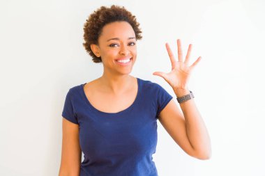 Beyaz arka plan üzerinde genç güzel Afrikalı Amerikalı kadın gösteren ve parmak numarası beş ile işaret kadar güven ve mutlu gülümseyen.