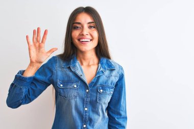 Genç güzel kadın rahat kot gömlek giyerek izole beyaz arka plan üzerinde duran gösteren ve emin ve mutlu gülümserken parmakları ile beş işaret.