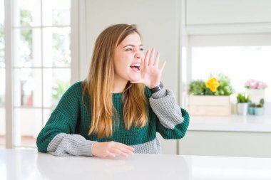 Genç güzel artı boyutu kadın rahat çizgili kazak giyen bağırarak ve ağızda el ile yan yüksek sesle bağırıyor. İletişim kavramı.