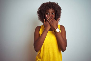 Izole beyaz arka plan üzerinde sarı t-shirt giyen genç Afrikalı afro kadın hata için elleri ile ağız kapsayan şok. Gizli kavram.