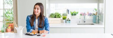 Güzel genç kadın doğum suşi yeme geniş açılı resim yüzünde gülümseme, doğal ifade ile yan bakıyor. Gülmekten emin.