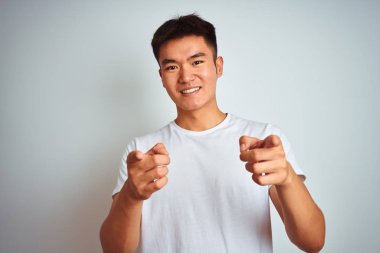 Genç Asyalı Çinli adam izole beyaz arka plan üzerinde duran t-shirt giyen mutlu ve komik yüzü ile kameraya parmaklarını işaret. İyi enerji ve titreşimler.