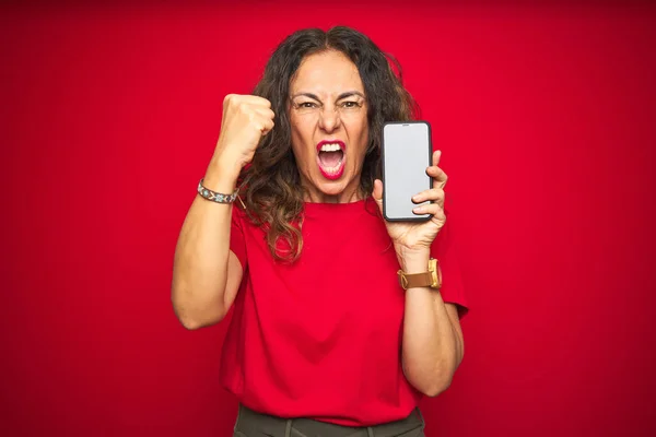 Średnim Wieku Starszy Kobieta Pokazując Ekran Smartphone Nad Czerwonym Białym — Zdjęcie stockowe