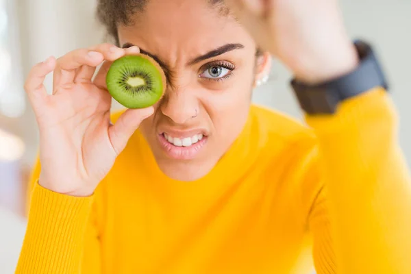 緑のキウイを食べる若いアフリカ系アメリカ人の女の子は怒り クレイジーと上げられた手で叫んでイライラし イライラし 怒りの概念 — ストック写真