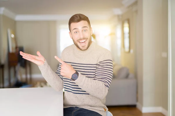 Joven Hombre Guapo Usando Suéter Casa Sorprendido Sonriendo Cámara Mientras — Foto de Stock