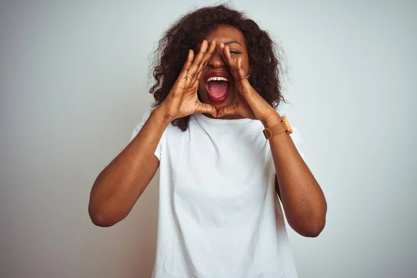 孤立した白い背景の上に立つTシャツを着た若いアフリカ系アメリカ人女性が口の上に手で大声で叫ぶ — ストック写真