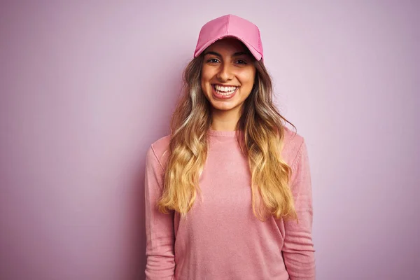 Young beautiful woman wearing cap over pink isolated background with a happy and cool smile on face. Lucky person.