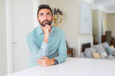 Yakışıklı İspanyol adam evde elleri çenesi ile soru, dalgın ifade düşünme. Düşünceli bir yüzle gülümsüyor. Şüphe kavramı.