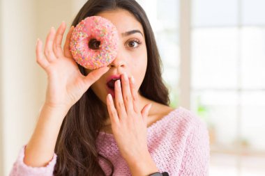 Güzel genç kadın ile göz üzerinde pembe donut ile bakıyor