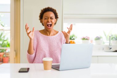 Genç afro-amerikan kadın bilgisayar dizüstü bilgisayar deli ve deli kullanarak çalışan bağırarak ve agresif ifade ve kollar kaldırdı ile bağırıyor. Hayal kırıklığı kavramı.