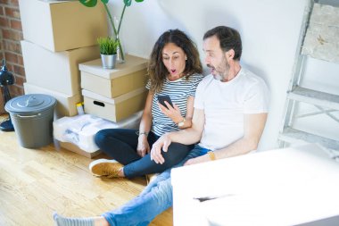 Akıllı telefonu kullanarak yeni bir eve taşınan orta yaşlı çift sürpriz bir yüzle şokta korkmuş, korku ve korku ifadesi ile heyecanlı