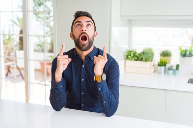 Yakışıklı İspanyol adam şaşırttı ve yukarı bakarak ve parmakları ile işaret ve kollarını kaldırdı şaşırttı.