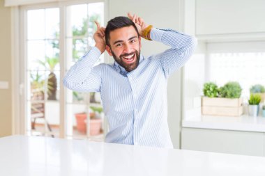 Yakışıklı İspanyol iş adamı komik ve tavşan kulakları gibi kafasına parmakları ile deli poz, neşeli gülümseyen